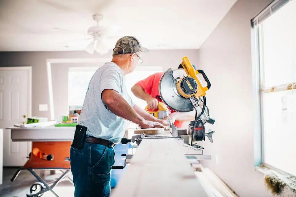 Tradesman using a mitre saw inside a bright room